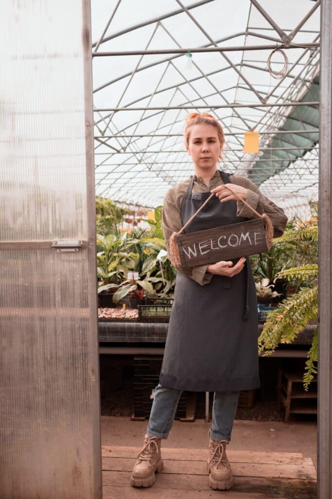 Small business owner with sign Welcome in garden store