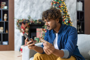 Cheated and upset Christmas man in living room near decorated Christmas tree, rejected and wrong